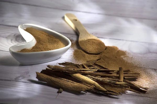 Beyaz ahşap arka plan-Cinnamomum verum izole toz bir tahta kaşık ve tarçın, tarçın