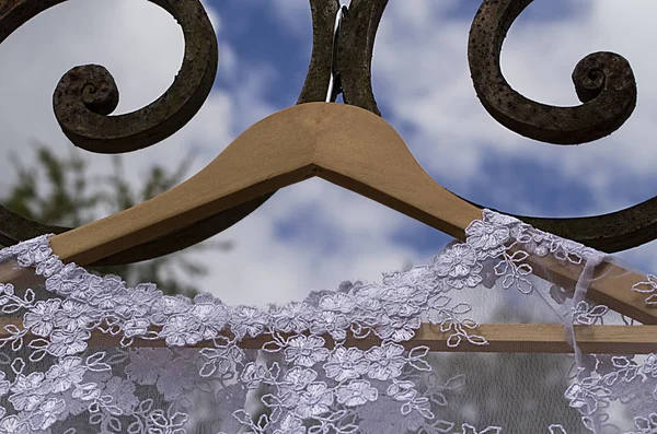 wedding dress - wedding dress hanging on hook with blue sky background- wrought iron