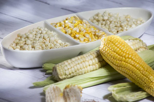 Mısır koçanı ve sarı mısır taneleri Beyaz ahşap arka plan-zea mays üzerinde beyaz cam vazoda