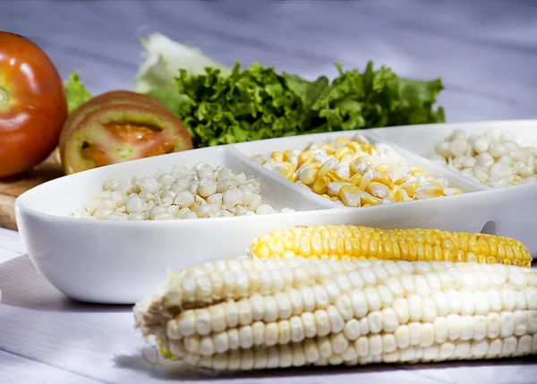 Beyaz ahşap arka planda - zengin salata tarafından - zea mays eşliğinde güzel beyaz kase mısır koçanı ve sarı mısır taneleri