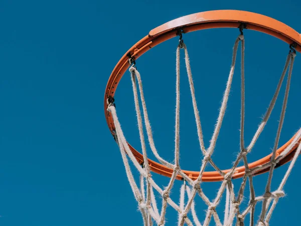 Isolated basketball net shot directly below and looking up with the blue sky as the background.Basketball basket
