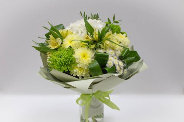 Buket kağıt ambalaj hafif bir arka plan üzerinde taze çiçek (sarı yeşil)