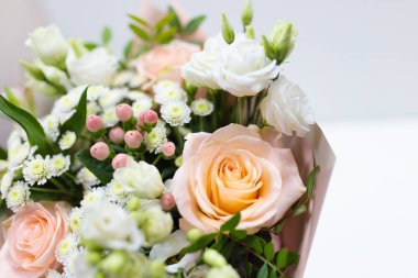 Narin buket taze çiçek (ana renkler: beyaz ve pembe) hafif bir arka plan üzerinde bir vazoda kağıt ambalaj.