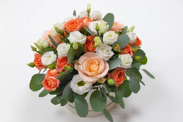 An impressive composition of roses and Eucalyptus leaves in a hat box (color: pink, pink, orange, green) on a light background
