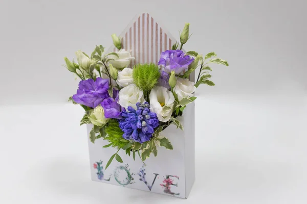 花的精致花卉布置 在一个盒子的形式 信封与题词爱 在一个浅的背景 尤斯托马 免版税图库照片
