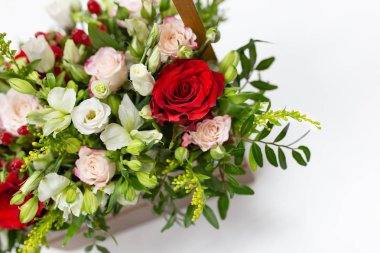 taze çiçekler, yeşillik ve çilek duygusal kompozisyon (yeşil, beyaz ve parlak kırmızı aksan ile açık yeşil) hafif bir arka plan üzerinde bir ip sapı ile ahşap bir kutu