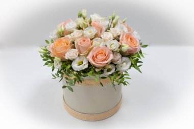 Wonderful flower arrangement in a hat box on a light background (Flowers: Rose, Eustoma. Colors: white, pink, beige) clipart