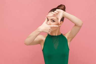 Kamera pembe bir arka plan üzerinde çerçeve fotoğrafçı işaret gösteren kadın