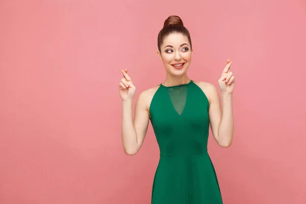Uśmiechnięta Kobieta Kok Fryzura Zieloną Sukienkę Skrzyżowane Palce Pozowanie Różowym — Zdjęcie stockowe