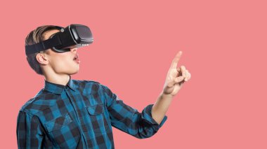 Genç adamla sürpriz: pembe bir arka plan üzerinde hayali gerçeğe dokunmak çalışırken vr kulaklık 