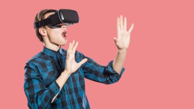 Genç adamla şok: pembe bir arka plan üzerinde hayali gerçeğe dokunmak çalışırken vr kulaklık 