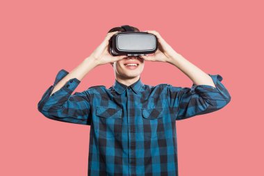 Mutlu gülümseyen genç adam VR kulaklık, pembe arka plan holding