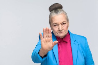 Mavi takım ve pembe gömlek gri arka plan, ifade duygu ve duyguları kavram kamera dur işareti gösterilen yaşlı büyükanne   