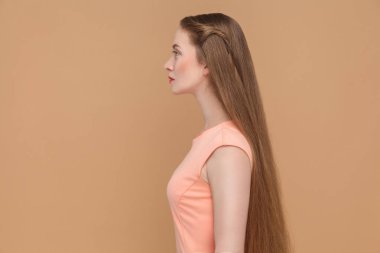 Pembe elbiseli uzun kahverengi saçlı güzel ciddi kadın yan görünüm açık kahverengi renkli üzerinde 