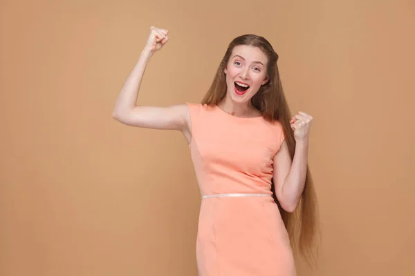 Erstaunte Gewinnerin Rosa Kleid Mit Siegeszeichen Auf Braunem Hintergrund — Stockfoto