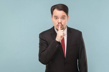 bıyık giyen ile iş adamı siyah takım elbise ve kırmızı kravat dudakları ile parmak ve şşş gösterilen dokunmadan açık mavi renkli üzerinde oturum   