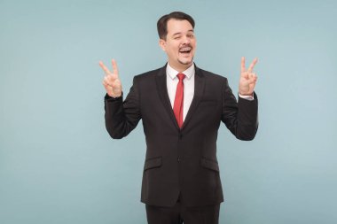 bıyıklı siyah takım elbise ve gülüyor ve açık mavi renkli kamera, barış belirtileri gösteren kırmızı kravat giyen işadamı  