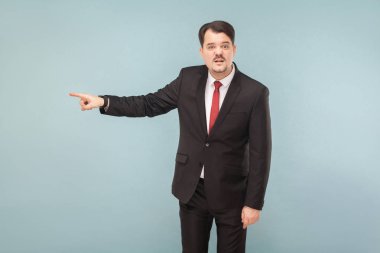 bıyıklı siyah takım ve kameraya bakarak ve açık mavi renkli bir kenara parmakla kırmızı kravat kızgın duygusal işadamı 