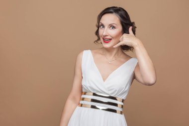 Çağrı merkezi işareti kahverengi arka plan üzerinde gösterilen beyaz elbiseli güzel orta yaşlı kadın