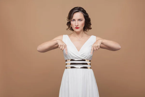 Mulher Séria Vestido Branco Apontando Dedo Para Baixo Fundo Marrom — Fotografia de Stock