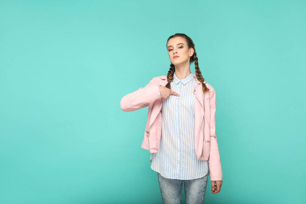 young woman with pigtail hairstyle showing Its me! gesture on blue background