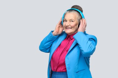 Mavi kulaklık müzik gri arka plan üzerinde tutarak renkli rahat tarzı moda mutlu Büyükanne