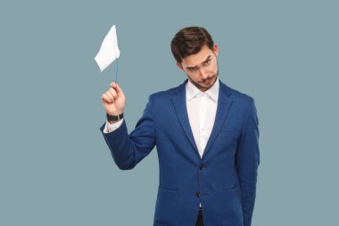 sad failure businessman in blue jacket and white shirt holding white flag and looking at camera with sad face on blue background  clipart