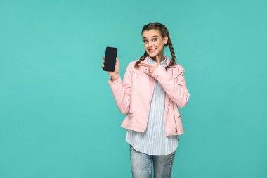 Hippi tarzı tutarak ve mobil ekranda yeşil arka planı gösteren helezon saç modeli ile mutlu güzel kadın 