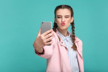 Hippi tarzı smartphone ve alma selfie öpücük yeşil arka plan üzerinde gösterilen süre tutarak helezon saç modeli ile güzel kadın 