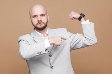 ciddi yakışıklı orta yaşlı kel ışık gri elbiseli kameraya bakarak ve pazı kahverengi arka plan üzerinde gösterilen işadamı sakallı