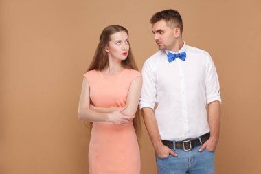 Yakışıklı adam beyaz gömlek ve mavi yay birbirine kahverengi zemin üzerinde ciddi yüzler ile arıyorum pembe elbiseli güzel sarışın kadınla portresi