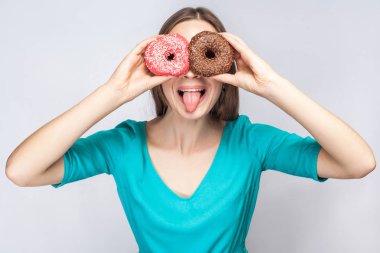 olumlu çılgın kadın mavi bluz donuts gözlerle kapsayan ve dilini gri arka plan üzerinde gösterilen süre gözlük yapma