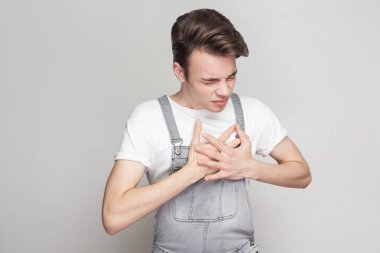 Çaresiz yüz ve gri arka plan üzerinde kapanış gözleri ile ağrı gidermek için meme için güçlü kalp ağrısı olan ve el basarak mutsuz hastalık adam portresi