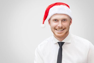 kameraya dişlek gülümseme ile ışık gri arka plan üzerinde seyir siyah kravat ve kırmızı yılbaşı şapka ile beyaz gömlekli mutlu yakışıklı işadamı portresi