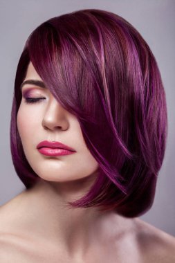 Güzel moda model kadın ile kısa mor renkli saç ve makyaj ile gri arka plan sakin kapalı gözler portre.