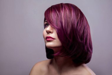 Güzel moda model kadın kısa mor renkli saç ve makyaj ve uzak gri arka plan üzerinde seyir ile portresi.