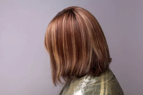 灰色の背景で強調表示された茶色の髪の女性の側面図 — ストック写真