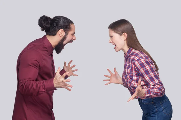 Profile side view of angry bearded man with black collected hair and woman in casual style looking and screaming at each other on gray background. — Stock Image Profile Side View Angry Bearded Man Black Collected Hair Woman Royalty Free Stock Photos