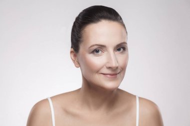 gri arka plan üzerinde doğal makyaj ile büyüleyici kadın portresi