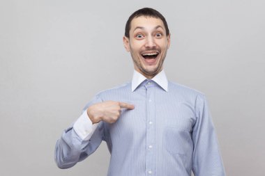 Sürpriz ve gri arka plan üzerinde kameraya bakarak heyecanlı işadamı 