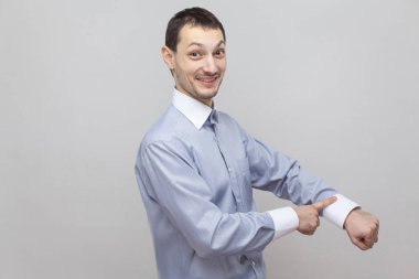 Gri arka plan üzerinde saat hareketi ile dişlek gülen işadamı portresi