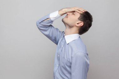 Yan görünümü üzgün kaybeden işadamı kötü duygular ve gri arka plan kafasına dokunmak portresi