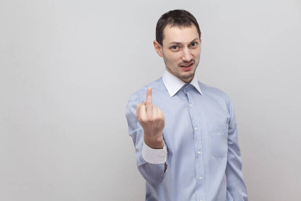 Portrait of angry businessman with middle finger fuck sign with poker face on grey background 