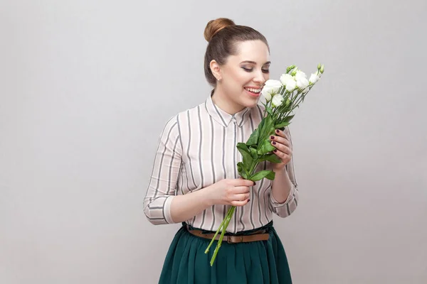ストライプのシャツ 緑のスカートが灰色の背景に白い花の花束の臭いがする美しい喜びロマンチックな若い女性 — ストック写真