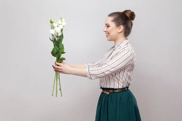 ストライプのシャツ 緑のスカートが灰色の背景に白い花の花束を持って魅力的なロマンチックな若い女性の側面図 — ストック写真