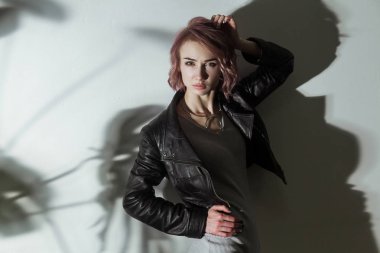 kadın gri elbise ve siyah deri ceket gri arka plan üzerinde poz 