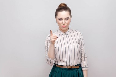 Çizgili gömlekli ve uyarı işareti gösterilen ve kameraya bakarak toplanan yasağı saç modeli ile yeşil etek ciddi güzel ve genç birbayan 