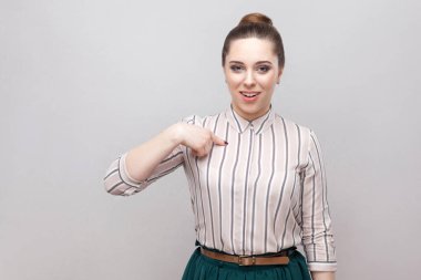 Kendini gösteren ve hayret suratla kameraya bakarak toplanan yasağı saç modeli ile çizgili gömlekli hayran güzel genç kadın portresi