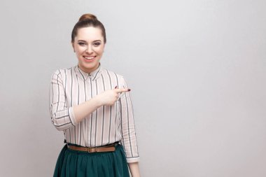 Çizgili gömlekli ve yeşil etek dişlek gülümseme ile ayakta ve bir kenara işaret toplanan yasağı saç modeli ile mutlu kadın 