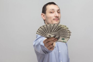 Veren ve gri arka plan üzerinde para hayranı paylaşımı mavi gömlekli memnun emin işadamı portresi.